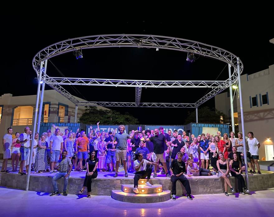 A full guest crowd with the Joy Boy team on a lit amphitheatre stage at night
